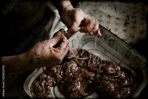 Old woman sewing the intestines of the pig, a necessary process during the elaboration of the sausages. photo