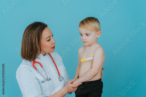 Woman doctor measures the temperature of a little boy