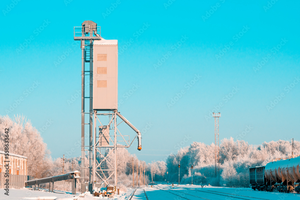 Obraz premium Grain elevator next to railroad during winter season
