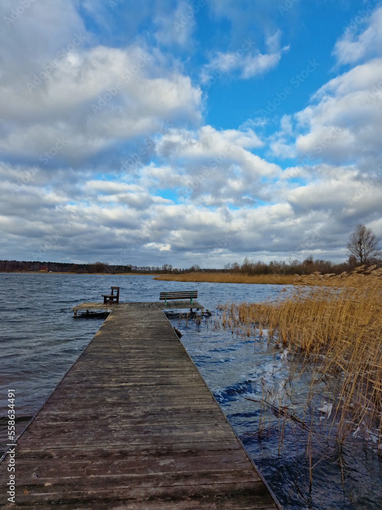 wooden old dock on lake with beautiful clouds in the blue sky