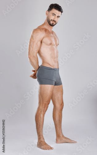 Фотография Portrait, body and a man underwear model in studio on a gray background to promote a brand of drawers