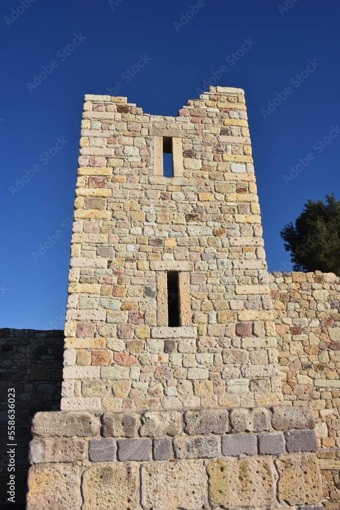 A classic Genoese castle in the Aegean from the Genoese era. Detailed stone walls of a ruined old medieval castle and a clear sky behind it. 