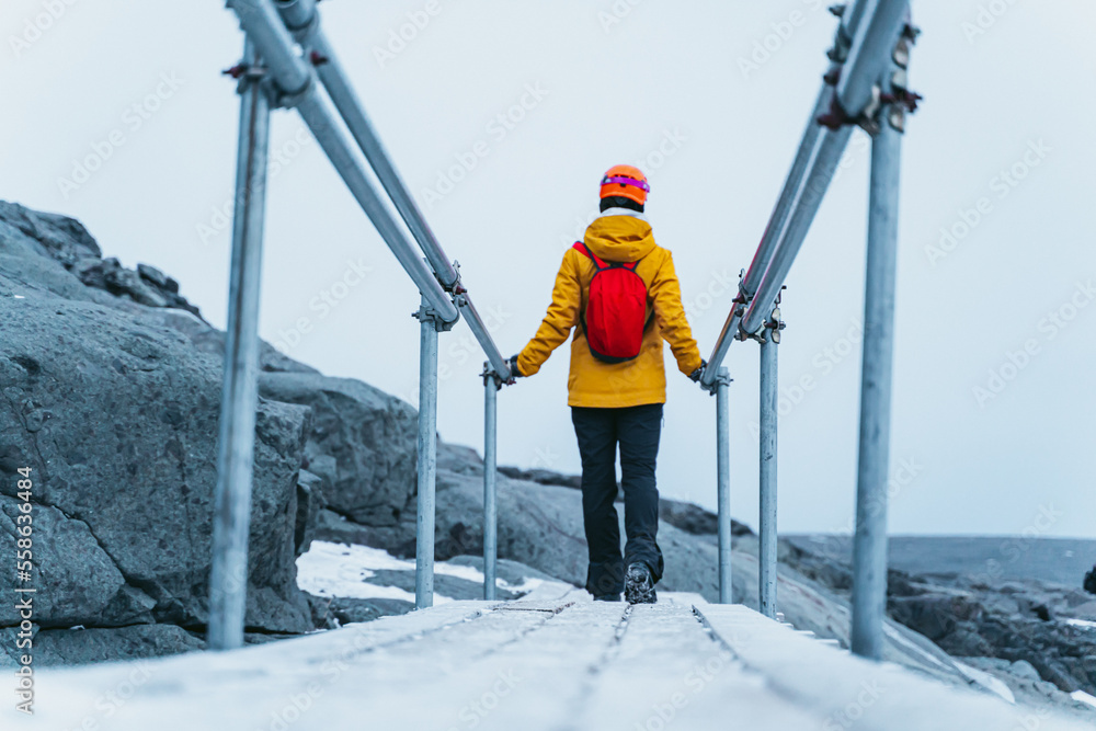 woman crossing an unstable wooden bridge.