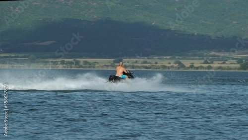 Watercraft, man riding jetski in the sea, speeding and enjoying the adrenaline with the waves splashing photo