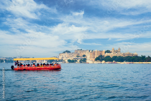 Udaipur, India - November 23, 2012: Toruist boat in Lake Pichola with City Palace in background. Udaipur, Rajasthan, India