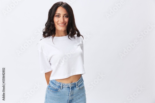 Woman in white t-shirt on white background brunette hands up gestures and signals poses in jeans emotion, lifestyle smiles, copy space