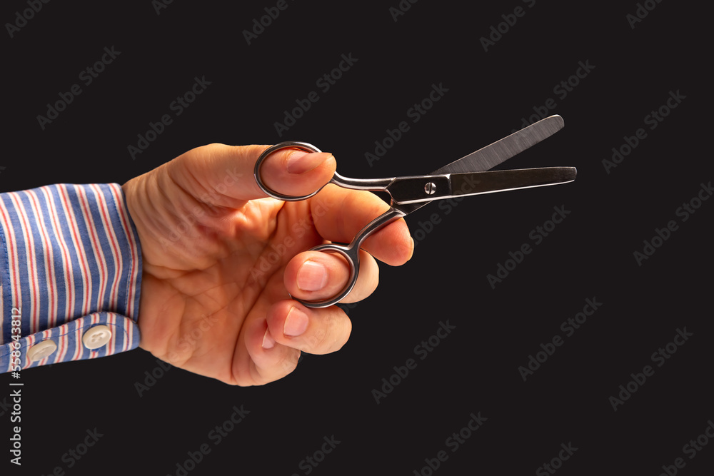 hand holds scissors on a dark background. tailor and barber profession