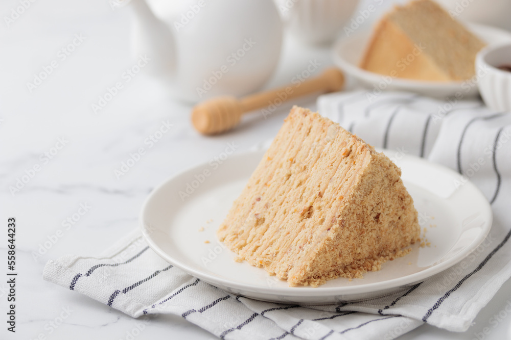 Piece Of Layered Homemade Honey Cake on the white table Piece Of Layered Homemade Honey Cake on the white table