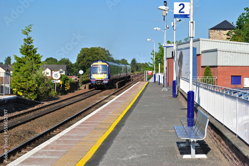 View Along Deserted Station Platform  with Benches and Approaching Train
