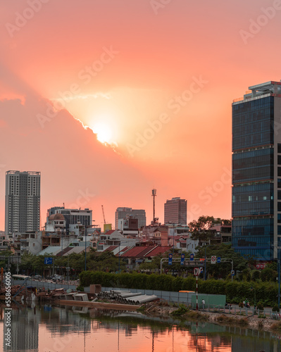 HOCHIMINH CITY  VIETNAM - JANUARY 19  2022  beautiful sunset sky with rare orange-pink color  the sun is round like egg yolk  foreground is Saigon river and old houses