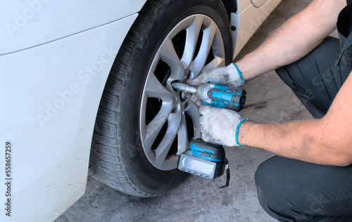 A car service worker unscrews the bolts on a car wheel. Car maintenance