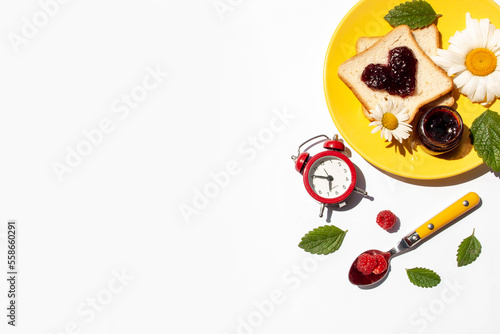 Breakfast with an alarm clock and a toast with a djem on a white background top view. sunny day photo