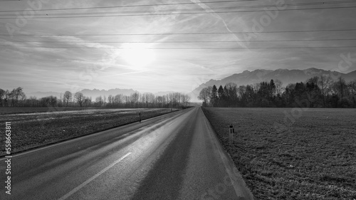 Highway in winter landscape with mountains in background in black and white © Manuel