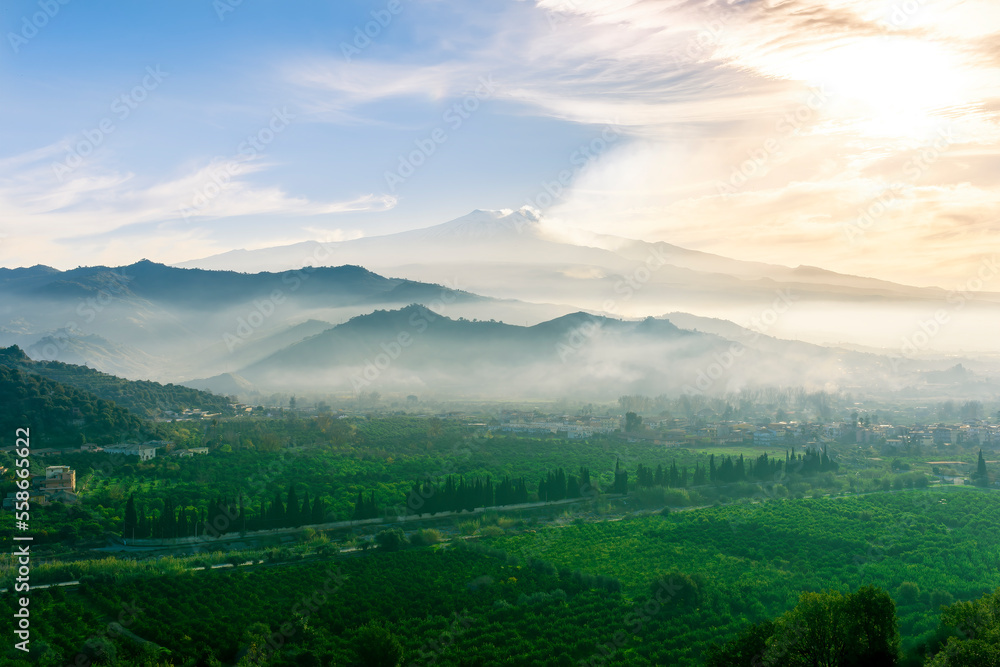 view at beautiful misty spring mountain valley with green gardens and mountains in mist on background of landscape