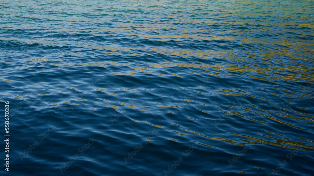 Waveless, calm sea at sunset. Pale sun rays reflecting off the sea. Waveless, calm sea at sunset. Pale sun rays reflecting off the sea.