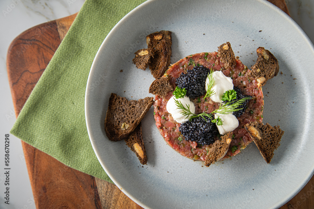 Tatar roh vom Rind mit schwarzen Kaviar, Schmand, Dill und Brot als ...