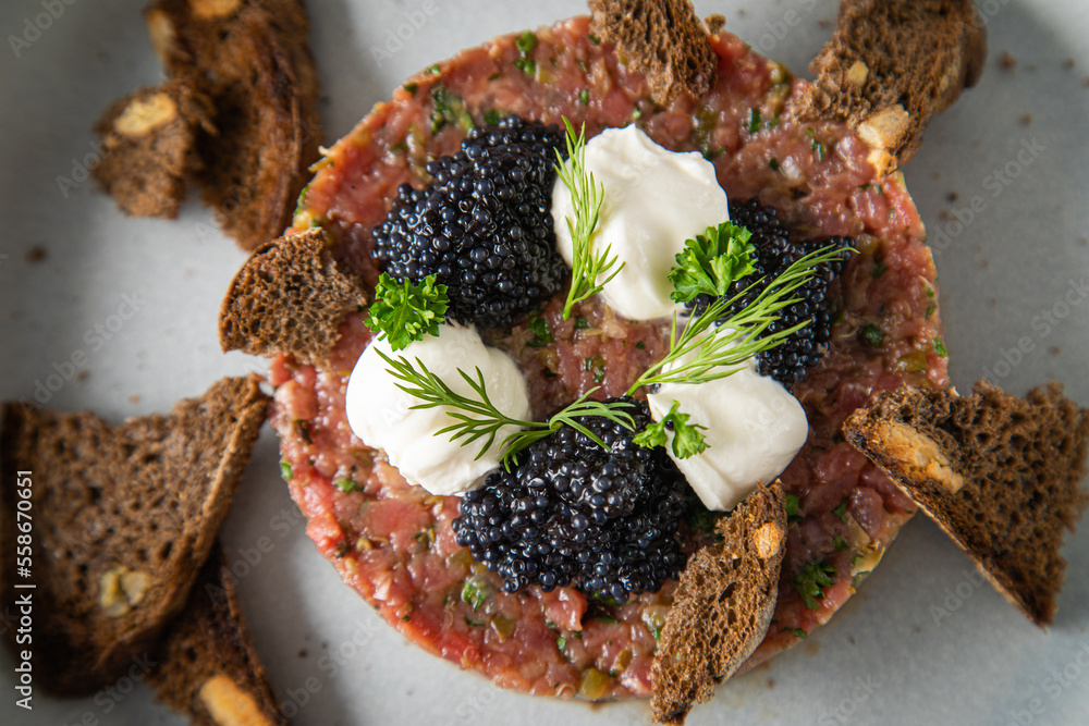 Tatar roh vom Rind mit schwarzen Kaviar, Schmand, Dill und Brot als ...