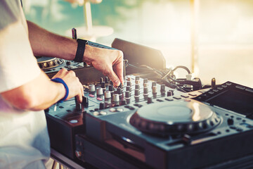 DJ is mixing music with deejay controller at outdoor summer pool party - nightlife people lifestyle concept