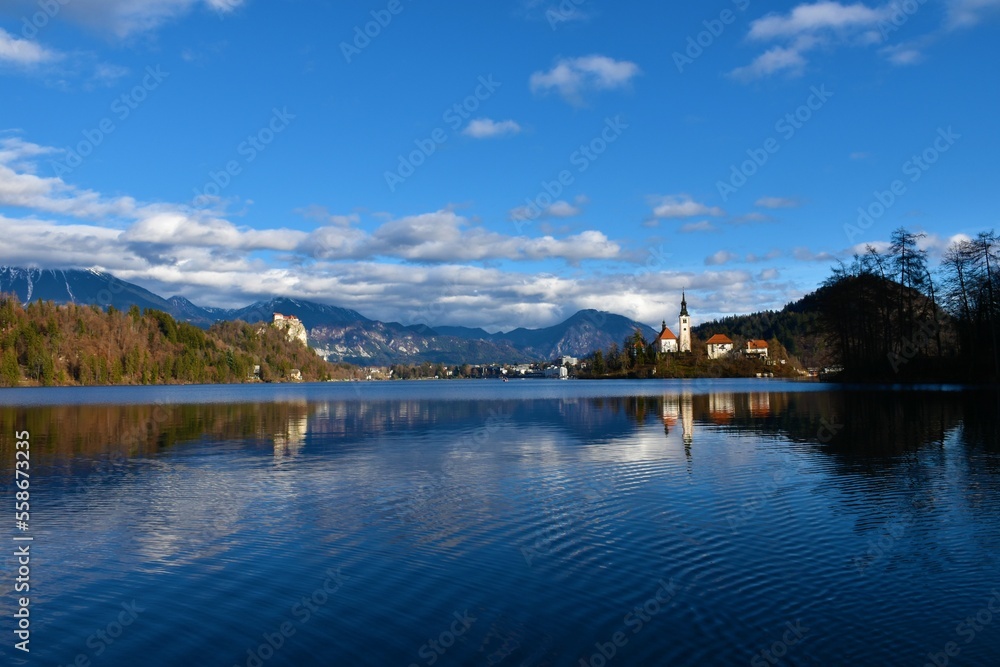 View of lake Bled with a medieval castle and the church of the assumption and cloud covered mountains in Gorenjska, Slovenia