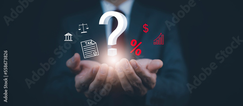 Tax with Ask question online concept, Businessman hold interface question marks tax payment optimization business finance, Concept of searching for an answer, Uncertainty, and problem-solving.