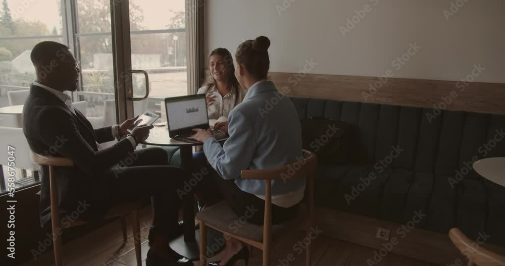 Three multiracial business people working together at a coffee shop Three multiracial business people working together at a coffee shop
