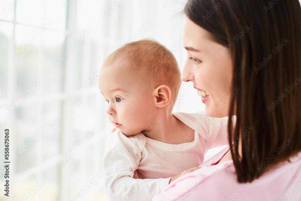 A young mother with a baby, son stands and looks out the window. A young mother with a baby, son stands and looks out the window.