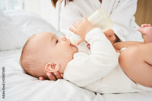 Close-up, little newborn baby, holding a bottle of baby food.
