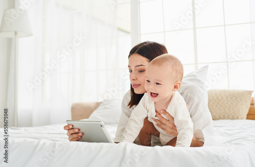 Nine-month-old baby with mom looking at the screen of a digital tablet.