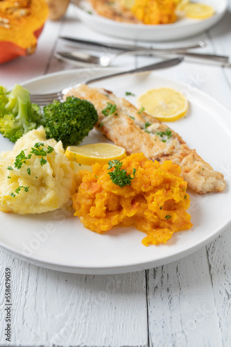 Fish fillet with mashed potatoes and red kuri squash puree. Served with broccoli on a plate