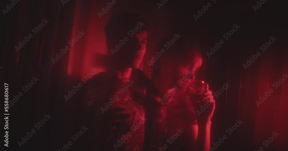 Two lgbt men in red light talking at a bar and drinking Two lgbt men in red light talking at a bar and drinking