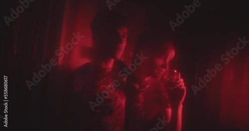 Two lgbt men in red light talking at a bar and drinking photo