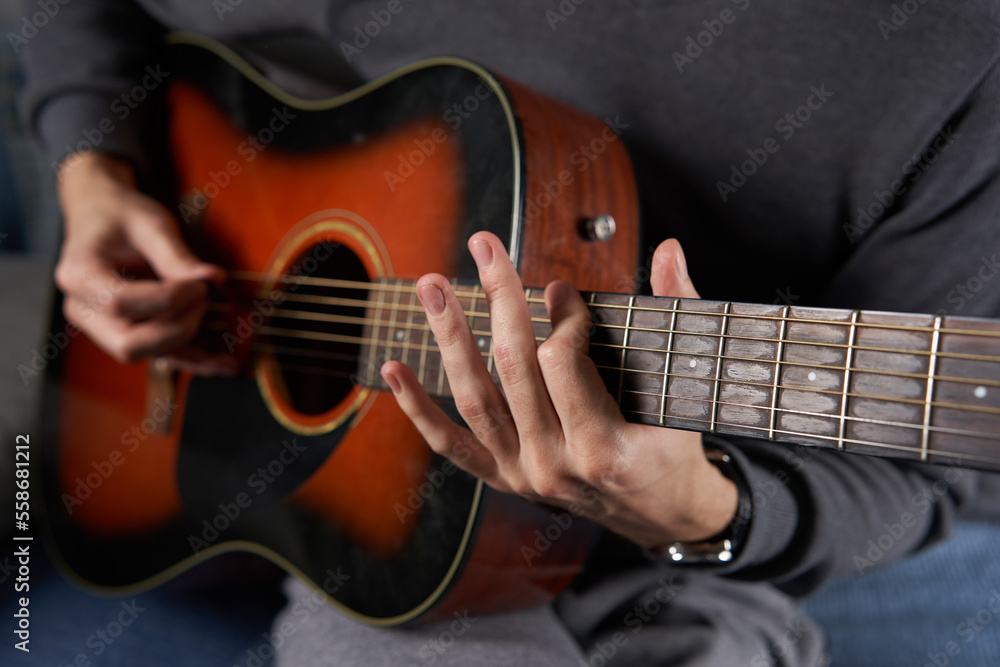 Fototapeta premium Young man playing guitar at home