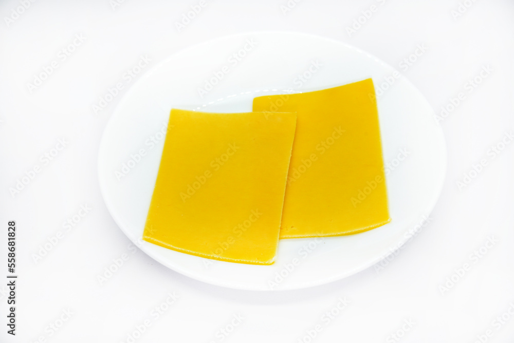 Pieces of melted cheese on a white plate. Chopped cheese. Slices of delicious cheese. Pieces of melted cheese on a white plate. Chopped cheese. Slices of delicious cheese.