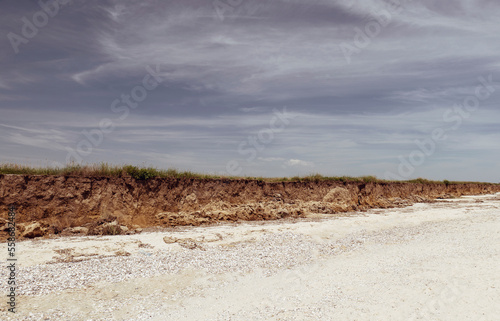 View of a long sea beach and a small canyon with grass. Beautiful sky with clouds. brown tint