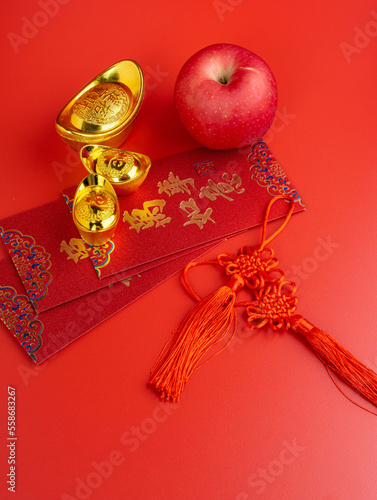 Happy Chinese New Year. Apple, Chinese Gold Sycee, angpao or red packet monetary gift for a symbol of prosperity. Isolated red. Copy space. Usable for wallpaper, greeting card, design.
