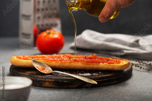 Olive oil is poured on bread, on top of which grated tomato is spread. Spanish traditional breakfast food photo