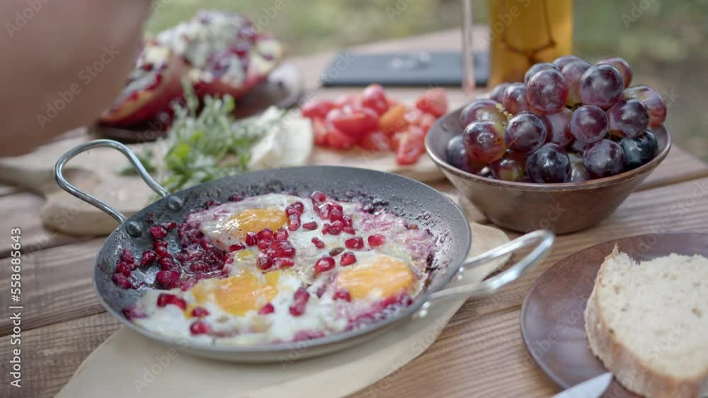 Cooking scrambled eggs with pomegranate. Cooking in the fresh air. An unusual recipe with pomegranate. Table is set Cooking scrambled eggs with pomegranate. Cooking in the fresh air. An unusual recipe with pomegranate. Table is set