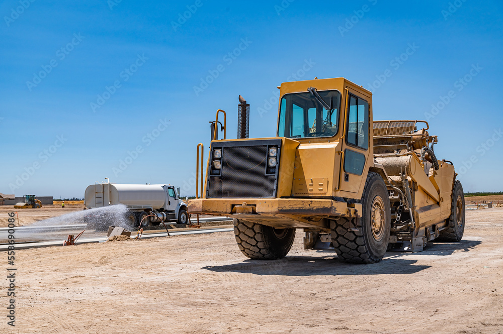 Obraz premium Yellow tractor. Watering machine. Road construction.
