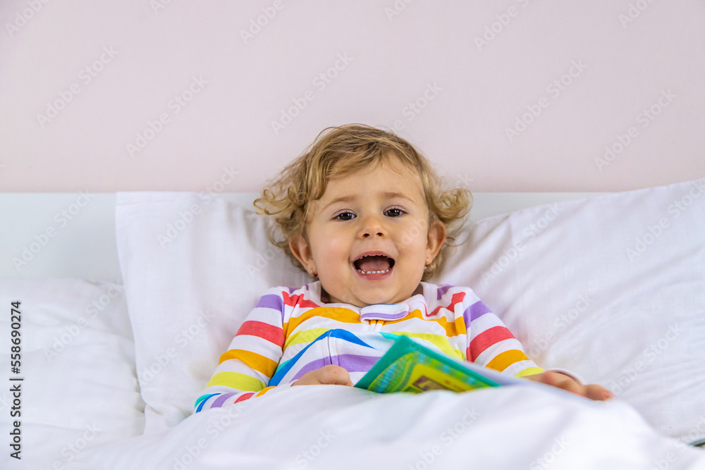 Children read a book in bed. Selective focus. Children read a book in bed. Selective focus.