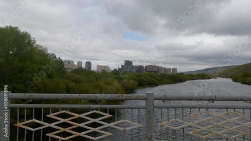 Car crossing the bridge over the river in the capital of Mongolia on the cloudy day. Ulaanbaatar city view, moody weather.