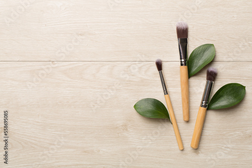Natural biodegradable makeup brushes on wooden background, top view © Liami