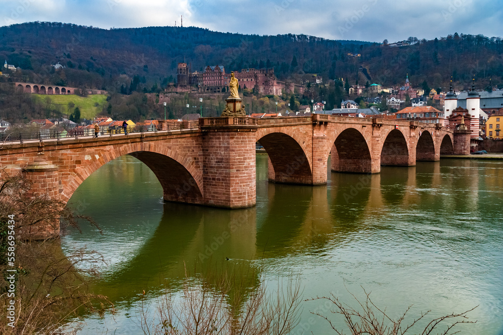 Nice view of Heidelberg's arch bridge Karl-Theodor-Brücke or Alte Brücke (Old Bridge) with its gate and two towers over the Neckar river. In the background is the castle ruin Heidelberger Schloss. 