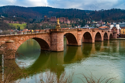 Nice view of Heidelberg's arch bridge Karl-Theodor-Brücke or Alte Brücke (Old Bridge) with its gate and two towers over the Neckar river. In the background is the castle ruin Heidelberger Schloss.  photo