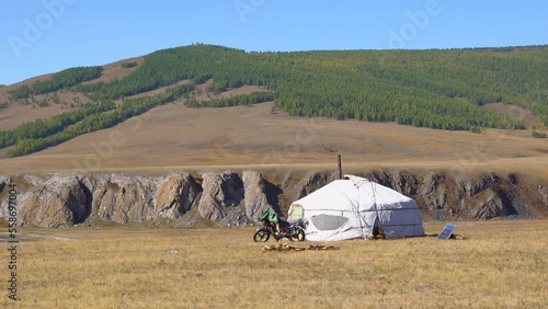 Nomadic persons yurt in rural Mongolian landscape. Ger tent on the foothill with beautiful mountains in the background on the sunny day. photo