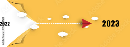 New Year plane track to point, line way. New Year 2023 concept, airplane flying over tearing apart yellow background, seeing 2022 and heading 2023.