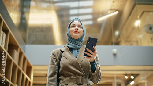 Print op canvas Portrait of Businesswoman Wearing Hijab Using Smartphone App to Share Social Media Post about Career Growth