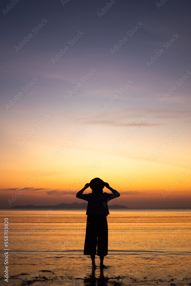 Fototapeta premium Silhouette beautiful Asian women is chilling on the beach with beautiful sunset