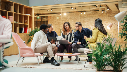 Wide Shot of a Multiethnic Group of People Discussing Ideas in a Meeting Room at Office. Businesspeople Making Creative Decisions For their Startup and Discussing Options photo