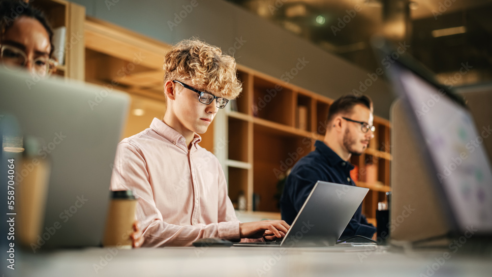 Diverse Multiethnic Creative Team Working On Laptops in Bright Busy Office. Portrait of Young Caucasian Man Using Laptop and Smiling. Male Developer Engineering a Software