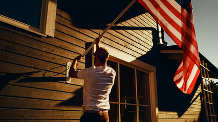 Patriotic Homeowner Raising the United States of America National Flag on His Neighborhood Home. Adult Man Proudly Flying the Flag on His Suburban House. Independence, Liberty, Freedom in USA Concept.